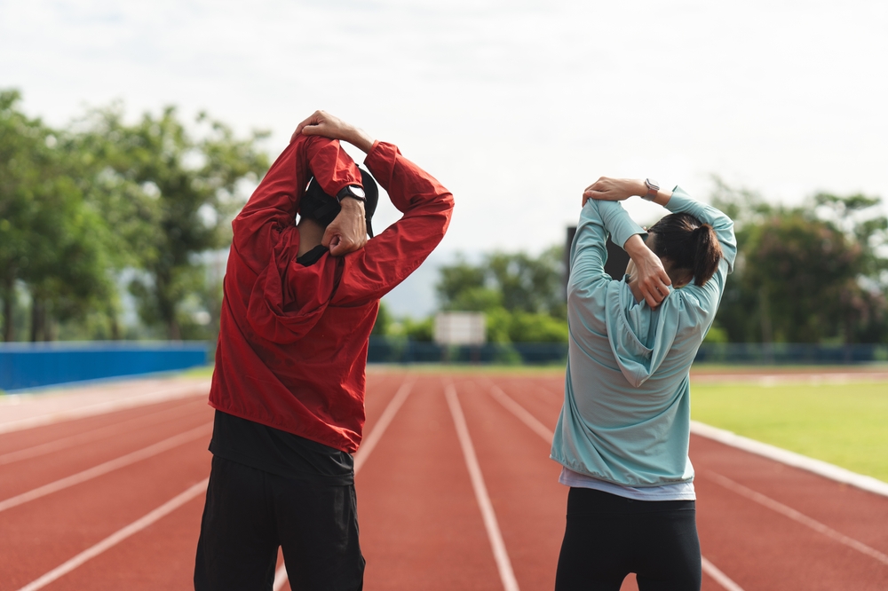 Two athletes stretch their arms before exercise, showing the importance of warm-ups for healthy movement. - Hastings Chiropractic