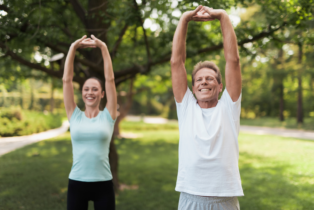 Outdoor Stretching Exercise for Wellness - Physiotherapy A man and woman stretch outdoors, promoting flexibility, strength, and healthy living through physiotherapy care. - Physiotherapy