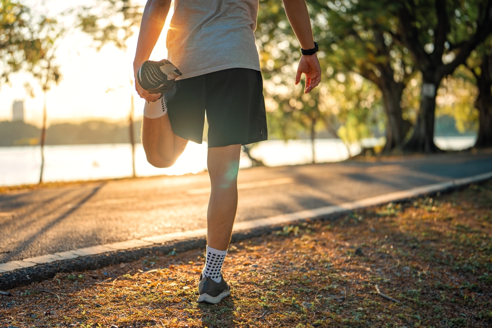 Outdoor Quadriceps Stretch Exercise - Hastings NE Massage A man stretches his leg muscles during an outdoor workout, promoting flexibility and recovery. - Hastings NE Massage
