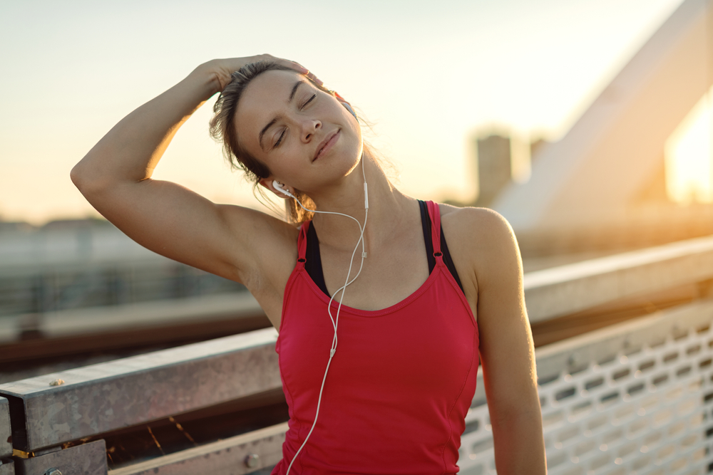 Woman Stretching Neck After Exercise - Chiropractic Adjustment A young woman stretches her neck post-workout, highlighting the importance of chiropractic care for flexibility and recovery. - Chiropractic Adjustment