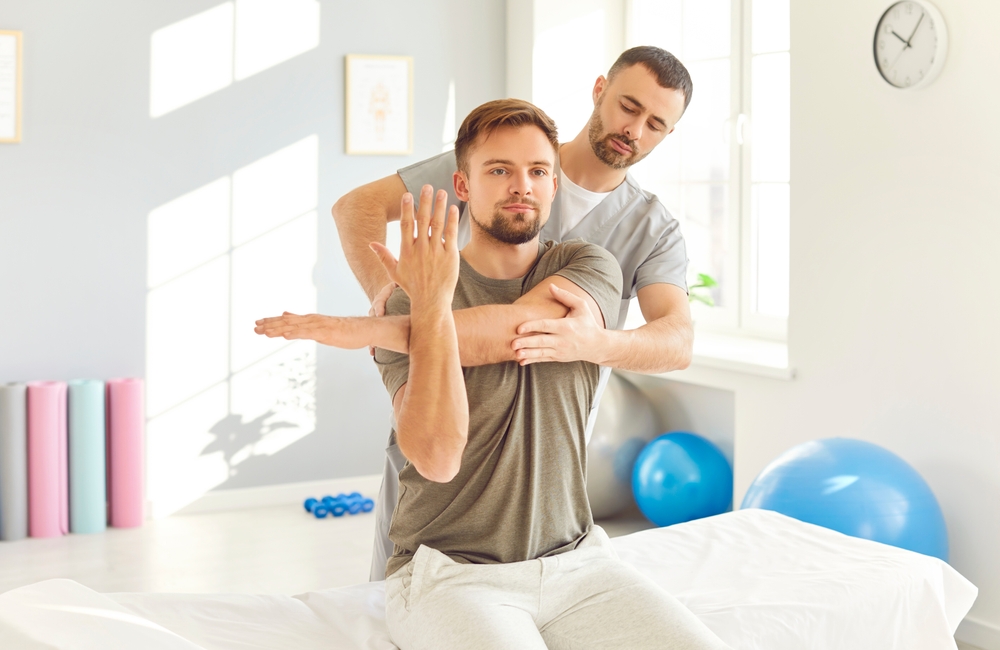 Assisted Shoulder Stretch with Physiotherapist - Physiotherapy A physiotherapist helps a patient perform shoulder stretches to restore flexibility and support rehabilitation. - Physiotherapy