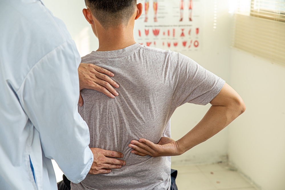 Chiropractor Examining Patient’s Back - Chiropractic Adjustment A chiropractor carefully examines a patient’s back to identify pain areas and improve spinal alignment. - Chiropractic Adjustment